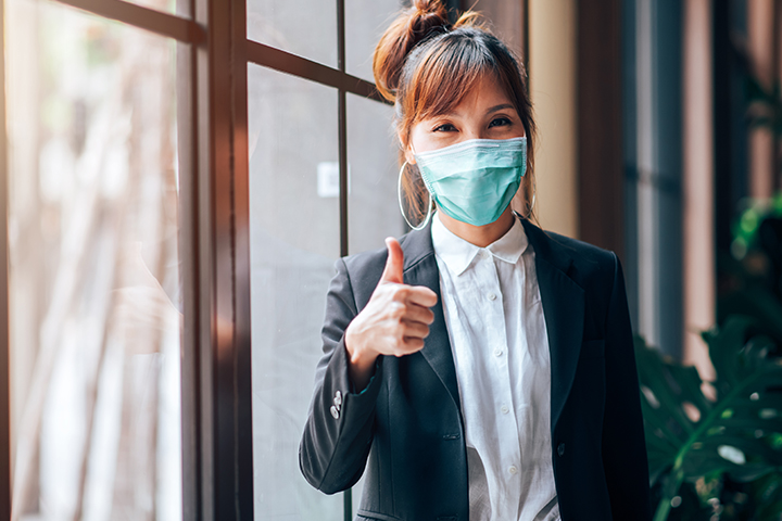 moments-matter-insurance-and-healthcare vrouw die een duim omhoog geeft, met een masker op