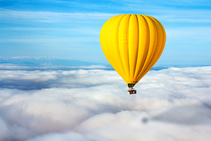 L'ascesa del dirigente dell'esperienza del cliente Mongolfiera gialla in un cielo limpido e blu con le nuvole