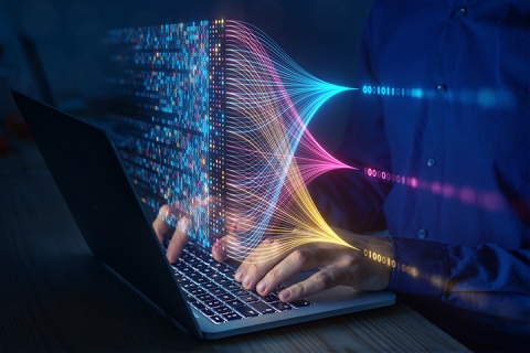 man typing on laptop with different colored data streams flowing in