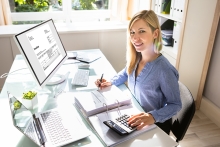 Young Businesswoman Calculating Bill With Computer And Laptop On Desk