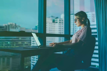 Femme travaillant sur un ordinateur portable à un bureau contre les fenêtres du condo