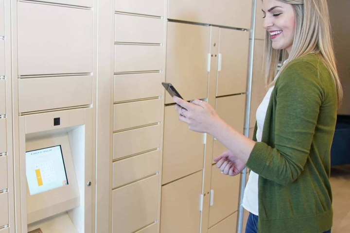 Woman collecting item at parcel locker with cell phone