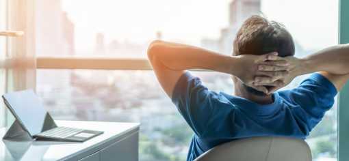 Man looking out the window with his hands placed behind his head Man looking out the window with his hands placed behind his head