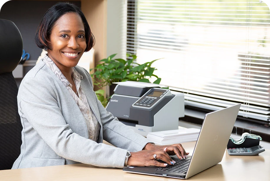 a woman using a laptop and smiling a woman using a laptop and smiling