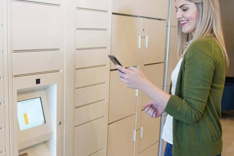 Woman collecting item at parcel locker with cell phone
