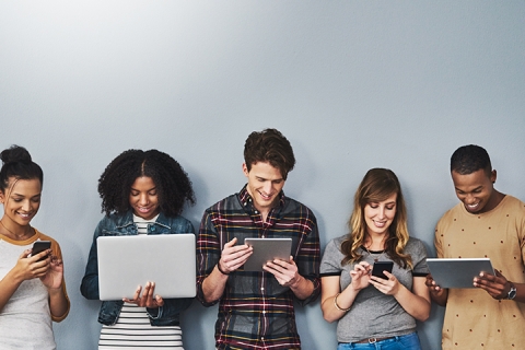 Studio shot of a group of young people using wireless technology against a gray background